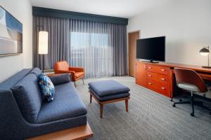 a living room with a couch and a tv in a hotel room at Courtyard Columbus Worthington in Worthington