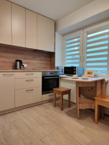 una cucina con armadi bianchi, tavolo e scrivania di Adelės apartamentai a Druskininkai