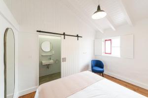 1 dormitorio con 1 cama y 1 silla azul en Engenho Hostel, en Lajes do Pico