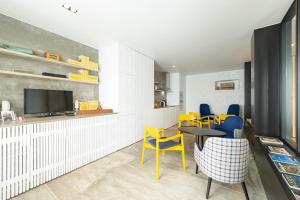 a living room with yellow chairs and a table and a tv at Engenho Hostel in Lajes do Pico