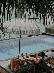 two people laying on lounge chairs next to a swimming pool at Aurora Beach View in Nusa Lembongan