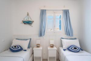 オルノスにあるLuxury Sea House By Blue Waters Mykonosの青いカーテンと窓が備わる客室で、ベッド2台が備わります。