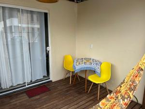 a table and chairs in a room with a window at SUITE RUA PESCADA AMARELA in Bombinhas