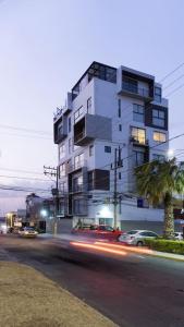 a tall white building on a city street with cars at ¡Fabuloso departamento céntrico y sanitizado! in Momoxpan