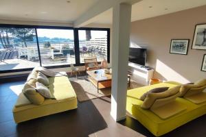 a room with a yellow bed and a living room with a view at Maison/Appart de standing vue mer in Guidel
