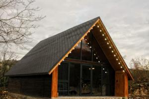 een hut met een zwart dak en verlichting bij Katskhi Cottage, Your Cozy Stay in Katsʼkhi