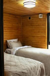two beds in a room with a wooden wall at Katskhi Cottage, Your Cozy Stay in Katsʼkhi