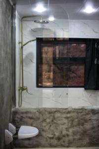 a bathroom with a shower with a toilet and a window at Katskhi Cottage, Your Cozy Stay in Katsʼkhi