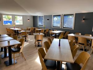 - une salle à manger avec des tables, des chaises et des fenêtres dans l'établissement B&B HOTEL Colmar Lumière, à Colmar