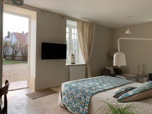 a bedroom with a bed and a tv and a window at EN VILLE à LA CAMPAGNE 2 in Louhans