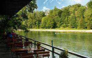 a restaurant with tables and chairs next to a river at Munich Central Camping in Munich