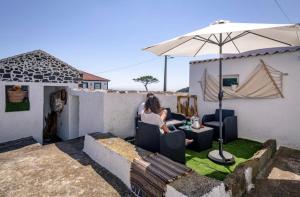 une femme assise sur une chaise sous un parapluie dans l'établissement Casa do Miradouro, à Santa Bárbara