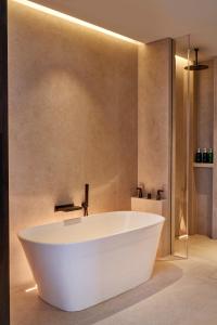 a large white bath tub in a bathroom at 1 Hotel Mayfair in London +48 photos