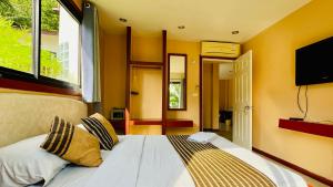 a bedroom with a bed with yellow walls and a flat screen tv at Sojourn 6 bedroom villa near Full Moon Beach in Koh Phangan