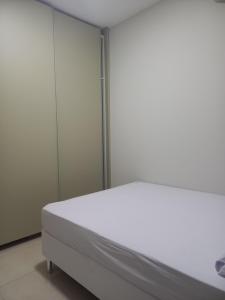 a white bed in a room with glass walls at Apartamento próximo ao centro com elevador! in Patos de Minas