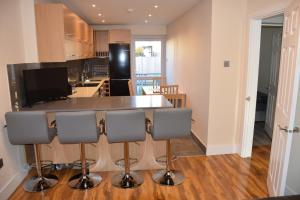 a kitchen with a bar with four chairs around it at Four Bedroom House Chandos Road in London