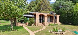 una pequeña casa de ladrillo en un patio con un árbol en La Calma, casa frente al río, gran parque y pileta en Villa Icho Cruz