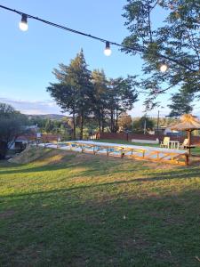 una valla de madera en un campo con mesa y sillas en La Calma, casa frente al río, gran parque y pileta en Villa Icho Cruz