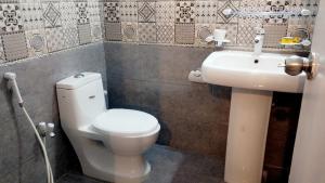 a bathroom with a white toilet and a sink at Shelton House in Karachi