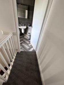 a bathroom with a toilet and a staircase with a sink at Glo Stay @ Hibbert Crescent in Skegby