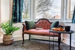 a red couch sitting in a window with a table at The Harrogate House - 4 Bed Townhouse in Harrogate