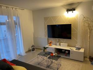 een woonkamer met een flatscreen-tv aan de muur bij Tina in Villeneuve