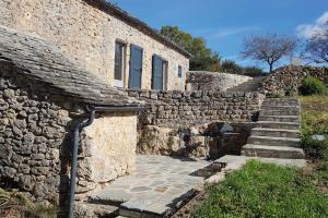 a stone building with stairs next to a stone wall at La Maison de Françoise in Les Vignes