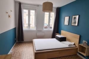 een slaapkamer met een bed met een blauwe muur bij L'olivier in Douai