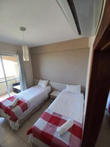 a bedroom with two beds and a window at Cumbuco Residence - Beach in Cumbuco