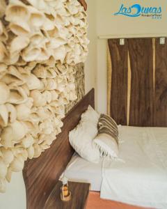 a bedroom with a bed and a wall covered in shells at Las Dunas Surf Resort in Aposentillo