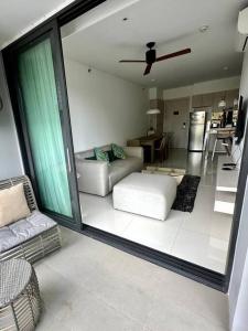 Квартира Cassia Residences Lake View في شاطئ بانغ تاو: غرفة معيشة مع أريكة ومروحة سقف