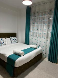 um quarto com uma cama com cortinas azuis e brancas em The pine 2 bedroom house California plaza em Nanyuki