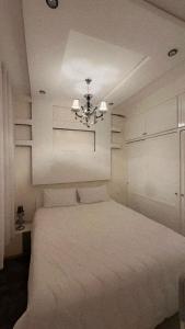 une chambre avec un lit blanc et un lustre dans l'établissement Well-furnished apartment in Tassila Agadir!, à Agadir
