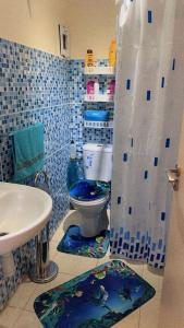 La salle de bains est pourvue de carrelage bleu, de toilettes et d'un lavabo. dans l'établissement Well-furnished apartment in Tassila Agadir!, à Agadir