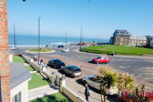 a street with cars parked in a parking lot next to the ocean at Longsands Beach, Apartment 2, Tynemouth in Tynemouth