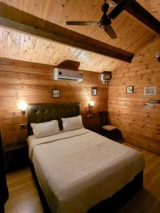 Schlafzimmer mit einem großen Bett und Holzwänden in der Unterkunft Greenland Cottage's Arambol in Arambol