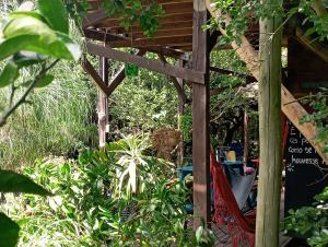 a pergola in a garden with plants at Nature Hostel in Barra de Valizas