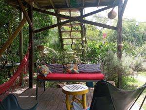 a pergola with a red bench on a patio at Nature Hostel in Barra de Valizas
