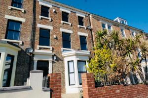 un edificio de ladrillo con un árbol delante de él en Longsands Beach, Apartment 2, Tynemouth, en Tynemouth