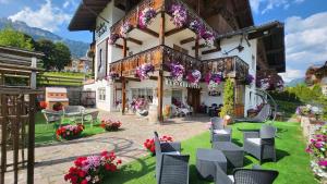 a patio with chairs and flowers in front of a building at Inter Hotel B&B in Vigo di Fassa