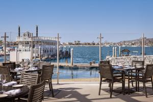 فندق باهيا ريزورت في سان دييغو: مجموعة من الطاولات والكراسي على رصيف مع قارب