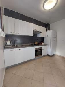 uma cozinha com armários brancos e um frigorífico branco em Charite Host Appartement , Wifi et Parking Gratuit em Agadir