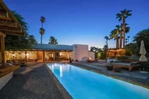 a swimming pool in front of a house with palm trees at Hacienda Hideaway in Rancho Mirage