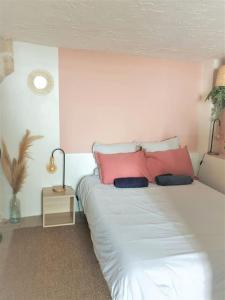 um quarto com uma grande cama branca com almofadas cor-de-rosa em Studio cosy dans le centre de Montpellier em Montpellier