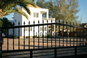 una cerca negra frente a una casa blanca en La Milagrosa Surf House & CoWork en Lajares
