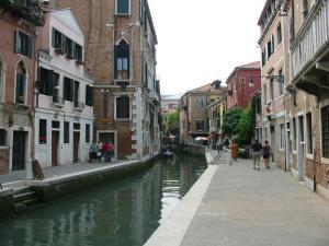 un canal en una ciudad con gente caminando por la acera en San Tomà en Venecia