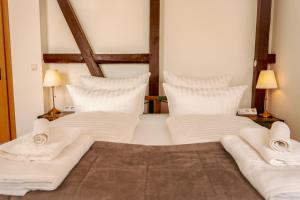 Bett mit weißer Bettwäsche und Kissen in einem Zimmer in der Unterkunft RISA Hotel Village - Engel & Kreuz in Gaggenau