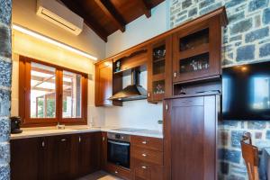 a kitchen with wooden cabinets and a stove top oven at Villa Ligaria, Lygaria in Agia Pelagia