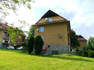 a small house on a green yard with cars parked at Apartman Dolica in Smokovce