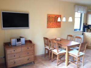 a dining room with a table and a television on the wall at Ferien unterm Reet in Prerow